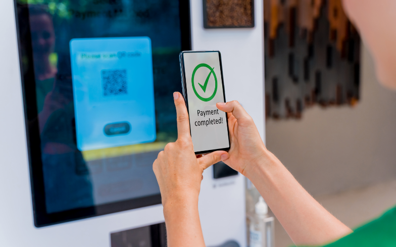 一位年轻女性正在使用无接触式支付购买咖啡，展示了AI智能售货柜的便捷性和高效性。bjl平台羚羊购AI智能售货柜解决方案通过快速部署、简化操作和云端远程管理，帮助上海某运营商实现售货机的智能化升级。